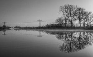 high voltage line, trees, water and mist, reflecting (black and white)