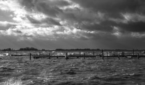 water, waves, wooden pier and clouds (black and white)